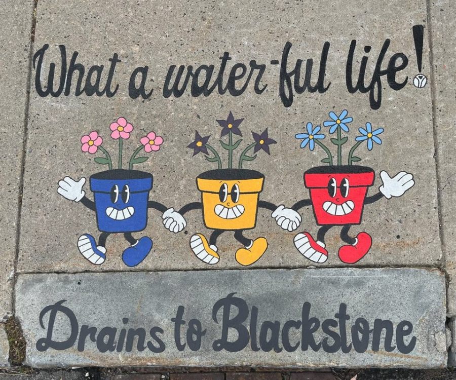 Finished mural of three cheerful flower pots (blue, yellow, red) with smiling faces, arms, and legs. The text above reads “What a water-ful life!” and below: “Drains to Blackstone.” The pots are holding hands and dancing across the sidewalk.